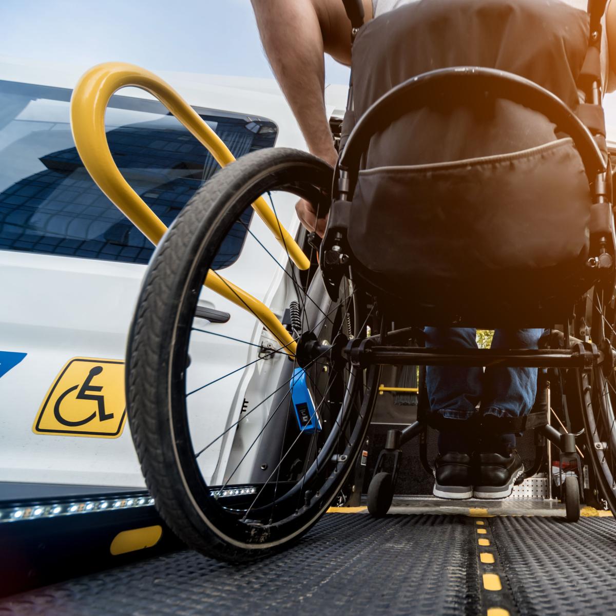 A man living with disability navigates the ramp of a shuttle bus from a wheelchair.