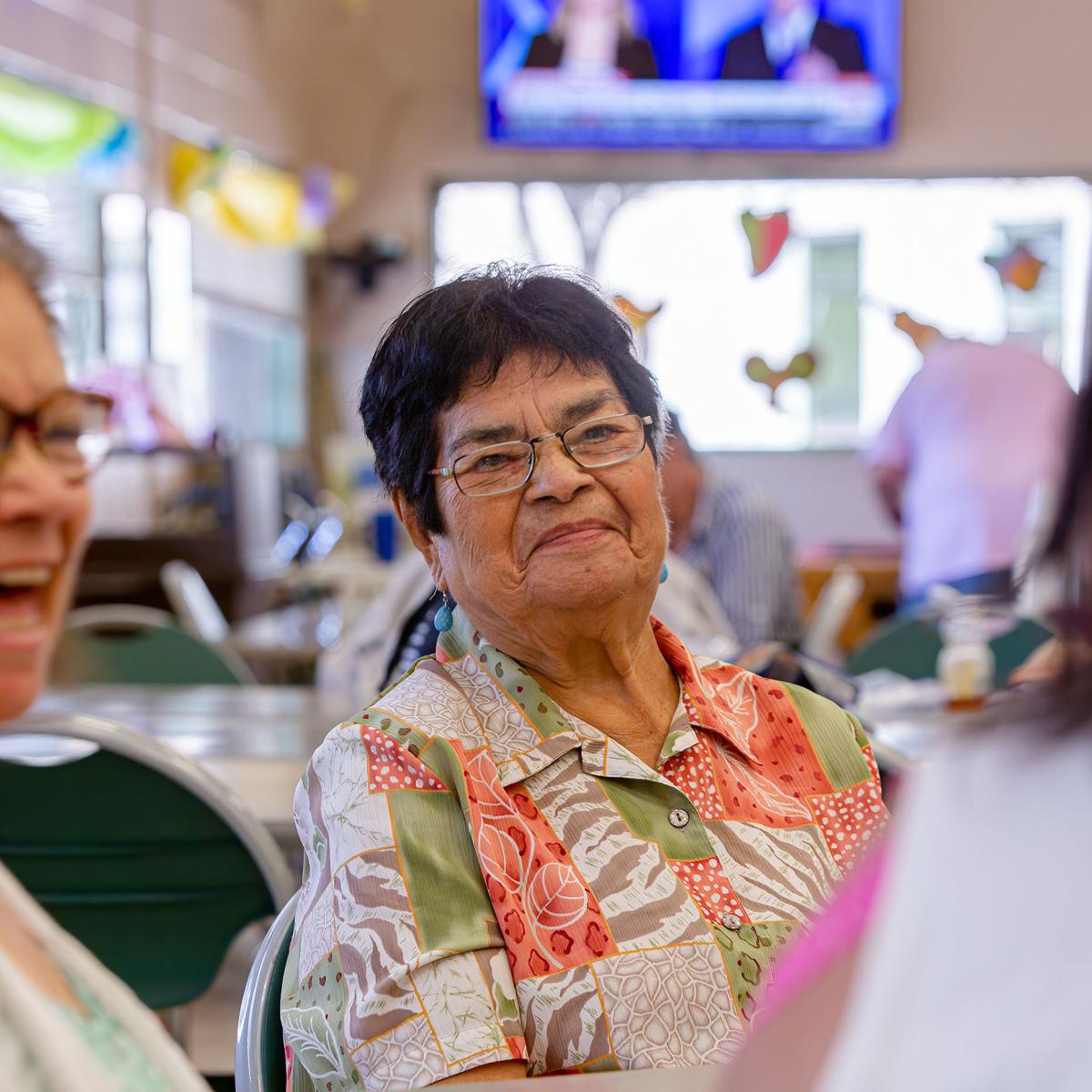 Older Adult Woman Smiles While Listening to a Conversation at a Senior Center